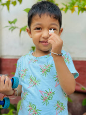 A cute kid wearing unisex topical print nightwear for kids and holding a flower leaf