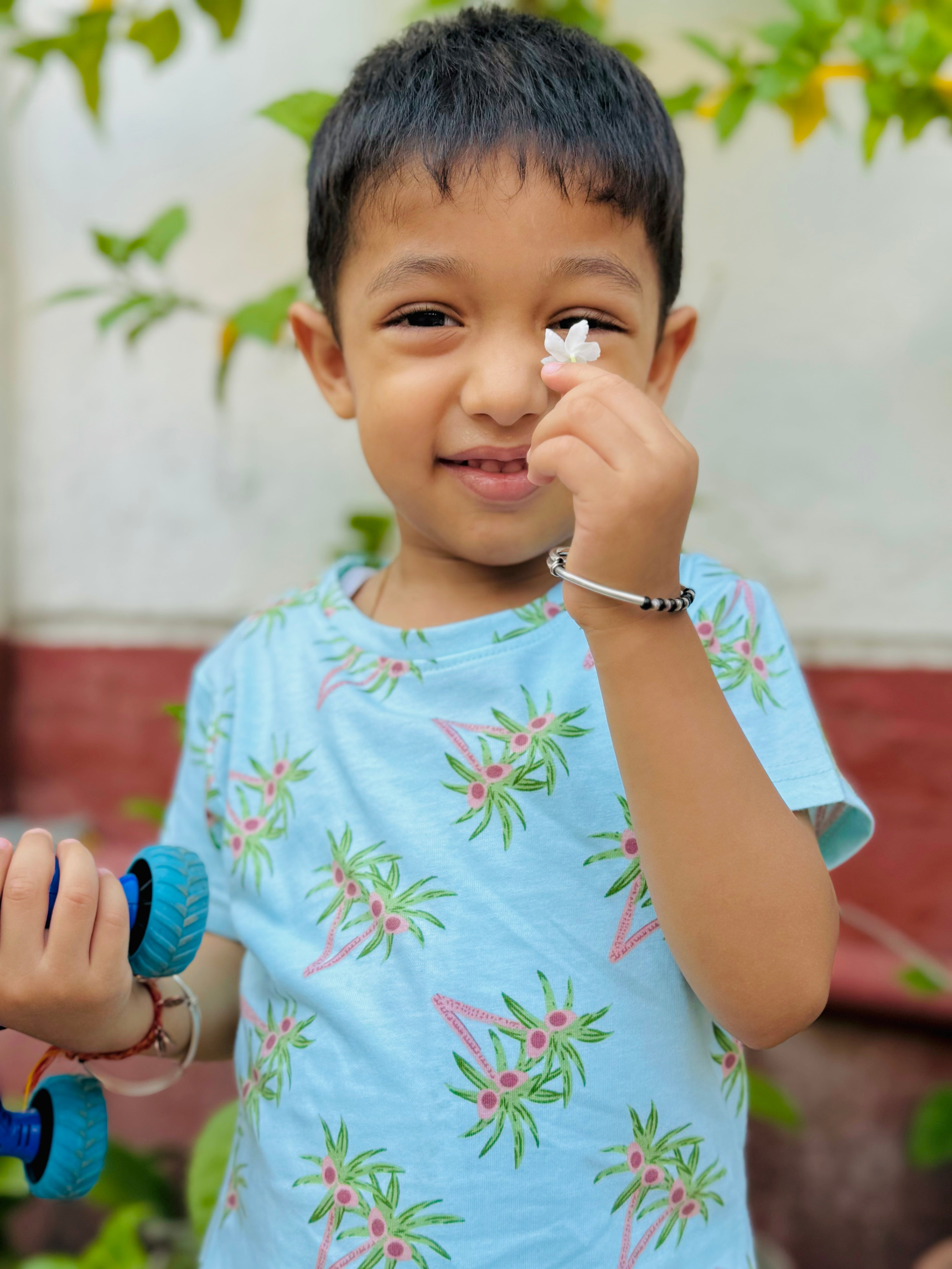 A cute kid wearing unisex topical print nightwear for kids and holding a flower leaf