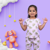 A cute girl wearing unisex topical print nightwear for kids, striking a confident pose