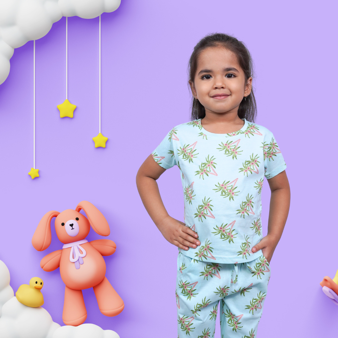 A cute girl wearing unisex topical print nightwear for kids, with one hand on her waist and the other in her pocket.