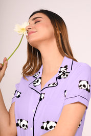 Woman wearing a purple Panda Print Shorts Set with panda graphics, holding a daisy flower.