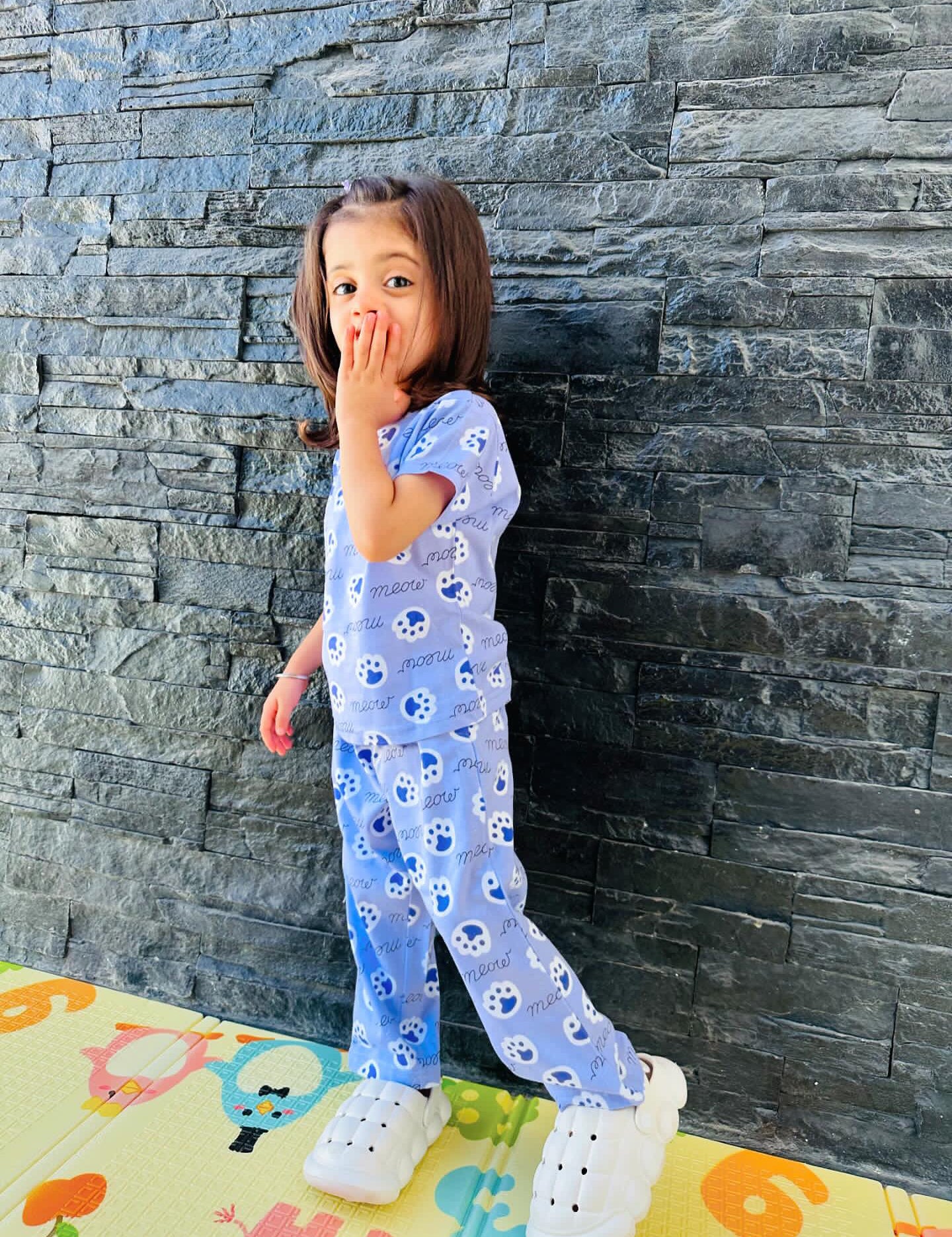 Child in Meow Kids Unisex Nightwear side view with kitten paws print.