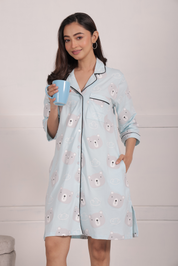 A girl standing with one hand in her pocket and holding a cup of coffee, wearing a Teddy Print Sleep Shirt nightwear by NapStory.