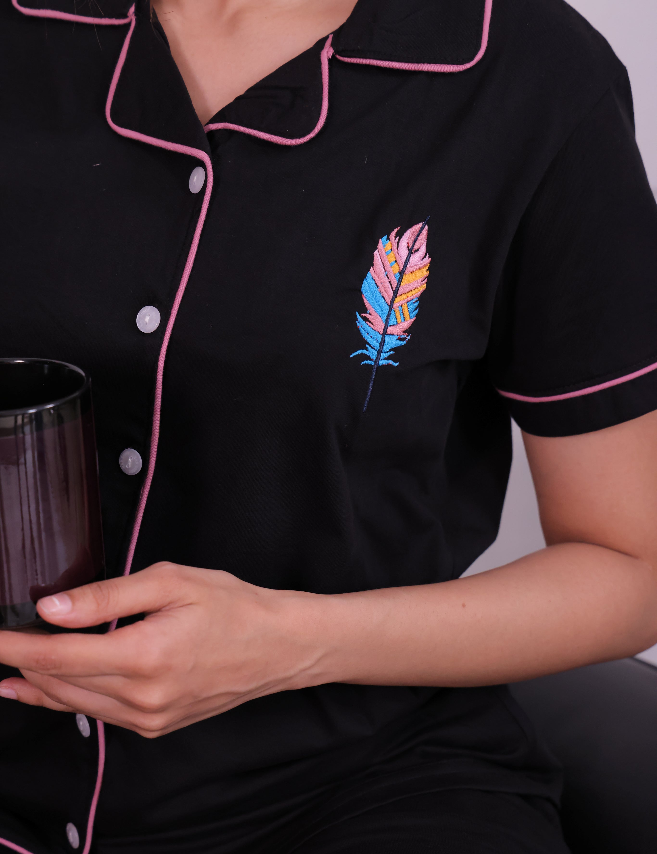 A lady showing the shirt of Feather embroidered premium nightwear pyjama set for women by NapStory