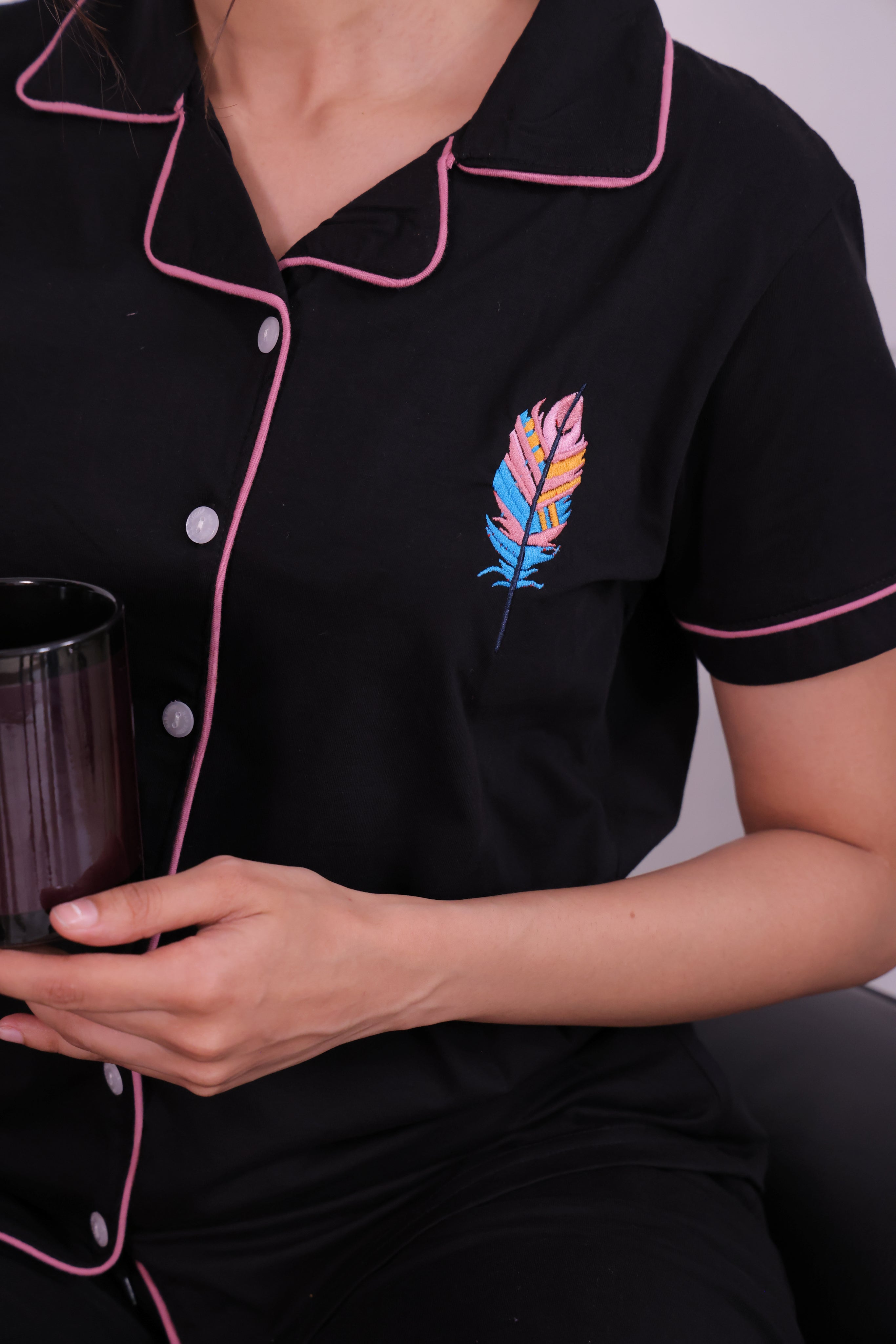 A lady showing the shirt of Feather embroidered premium nightwear pyjama set for women by NapStory