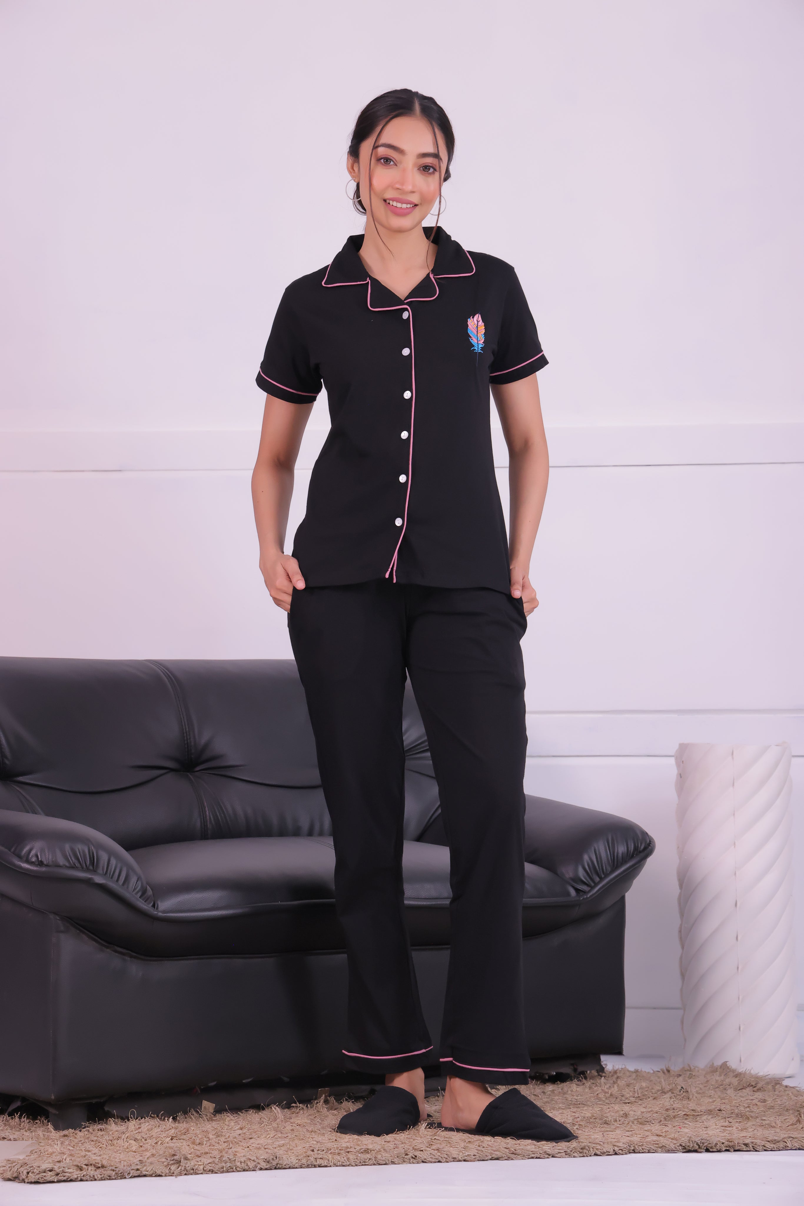 A lady standing next to sofa wearing Feather embroidered premium nightwear pyjama set for women