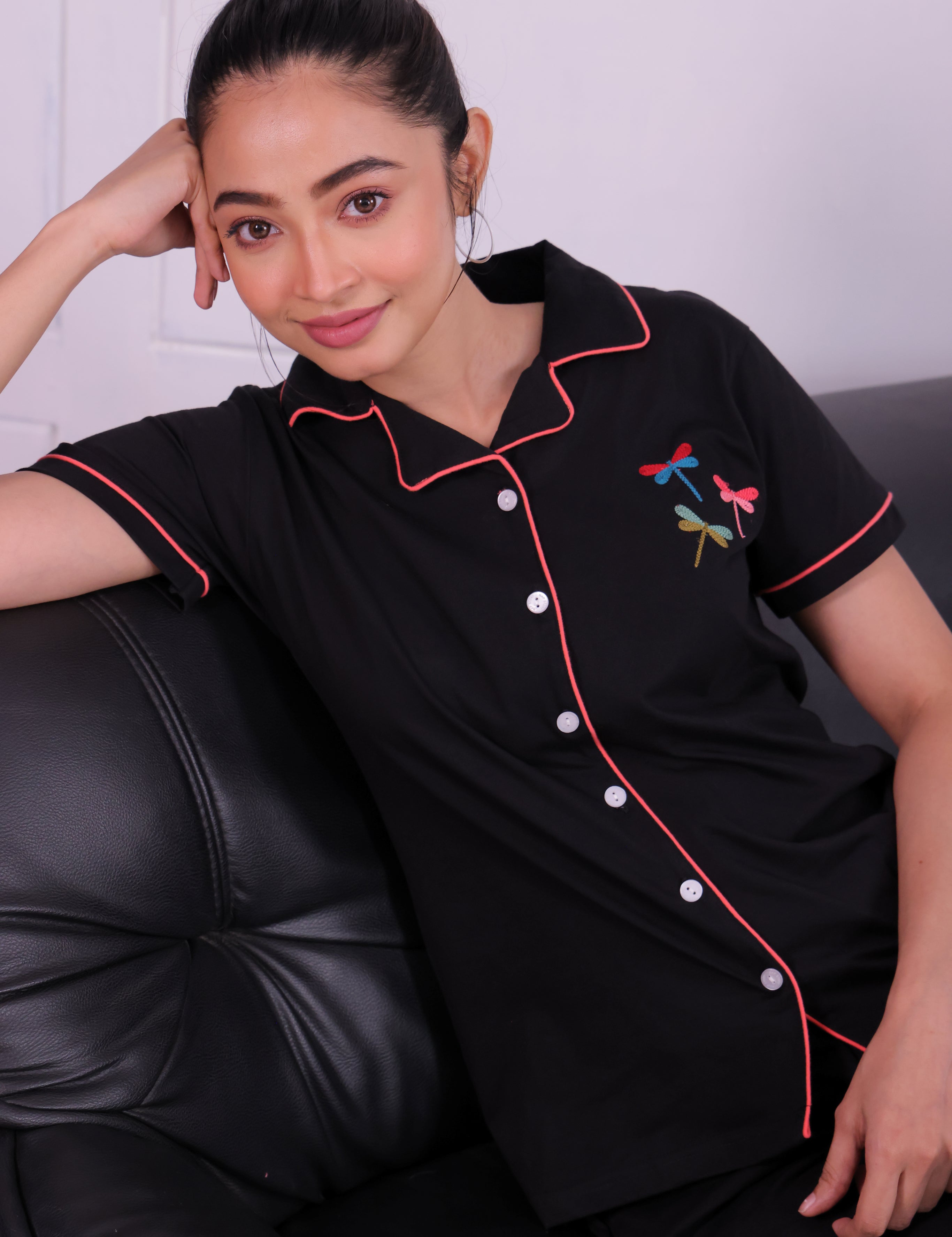 Young lady sitting comfortably on a sofa, wearing a Black Colour Dragonfly Embroidered Premium Pyjama Set nightwear by NapStory