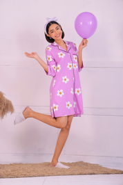 Young girl in a Pink Colour Poppy Print Sleep Shirt nightwear by NapStory, standing playfully with a balloon.