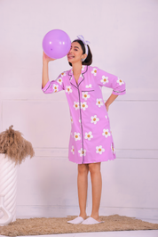 Young girl in a Pink Colour Poppy Print Sleep Shirt nightwear by NapStory, standing with a balloon in hand in a naughty pose.