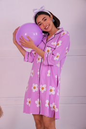 Young girl in a Pink Colour Poppy Print Sleep Shirt nightwear by NapStory, playfully resting her head on a balloon.