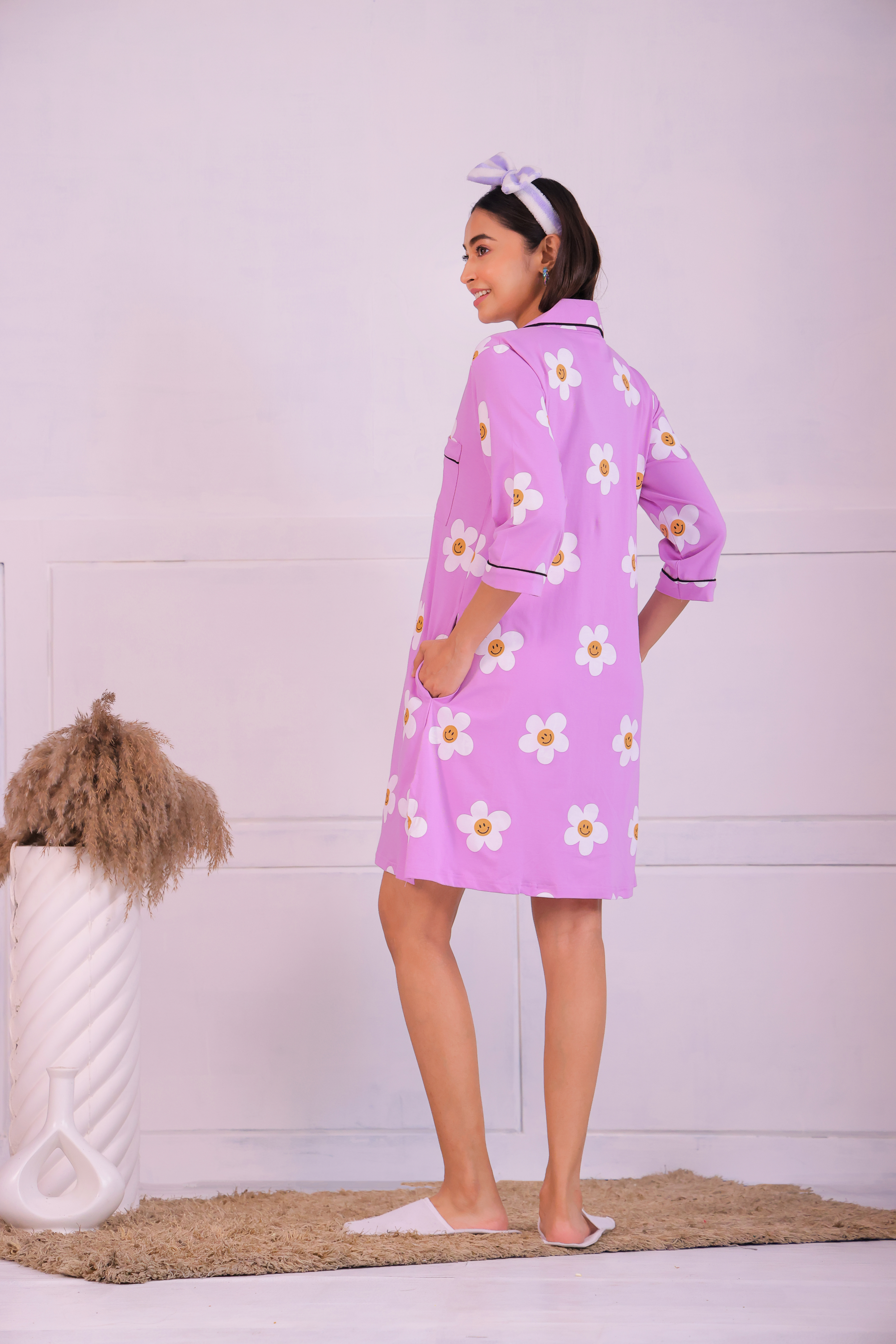 Young girl in a Pink Colour Poppy Print Sleep Shirt nightwear by NapStory, in a back pose with hands in pockets.