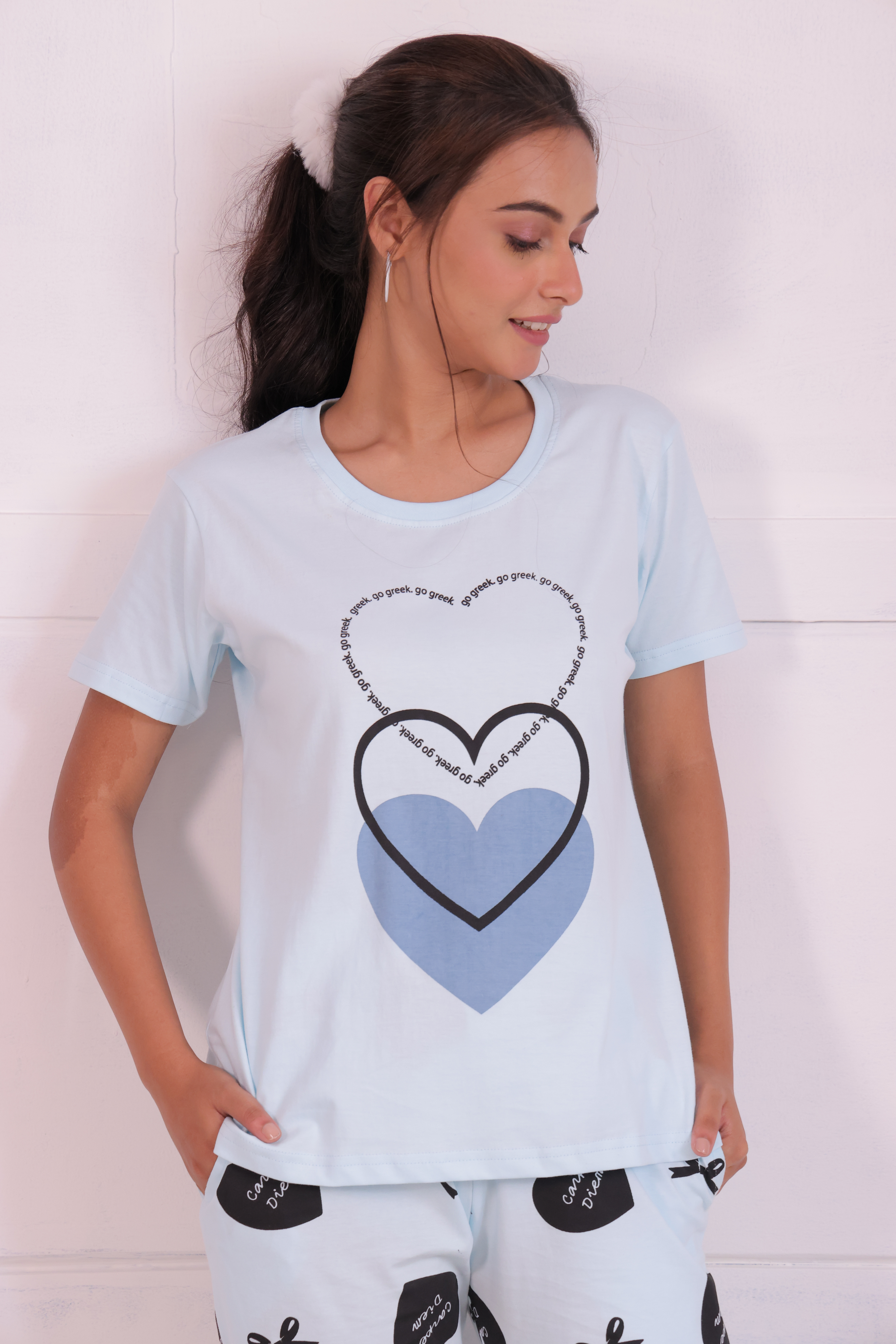 A young woman wearing stylish white colour bows and heart print nightwear t-shirt pyjama set.