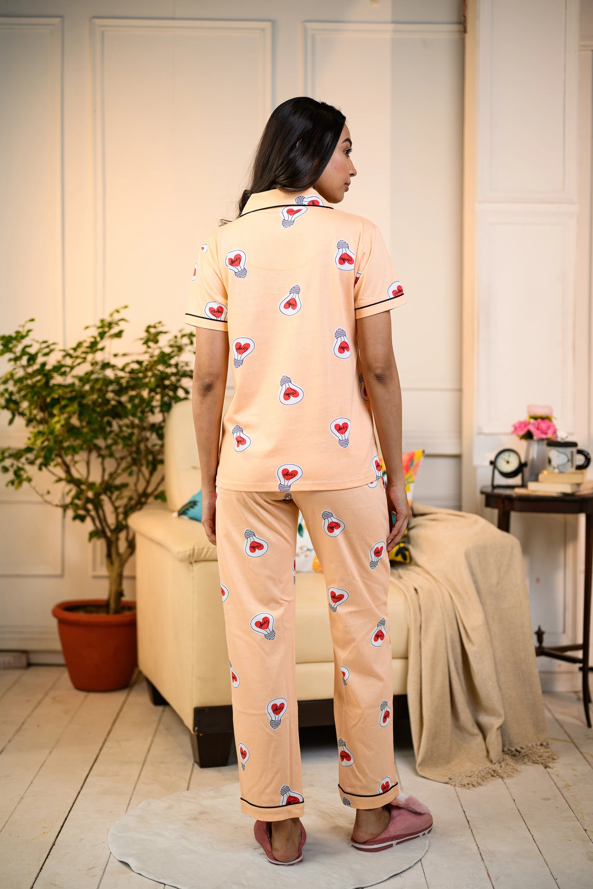 Back view of a woman wearing a peach Love Bulb Print Pyjama Set by NapStory, showcasing the playful bulb patterns and relaxed fit.