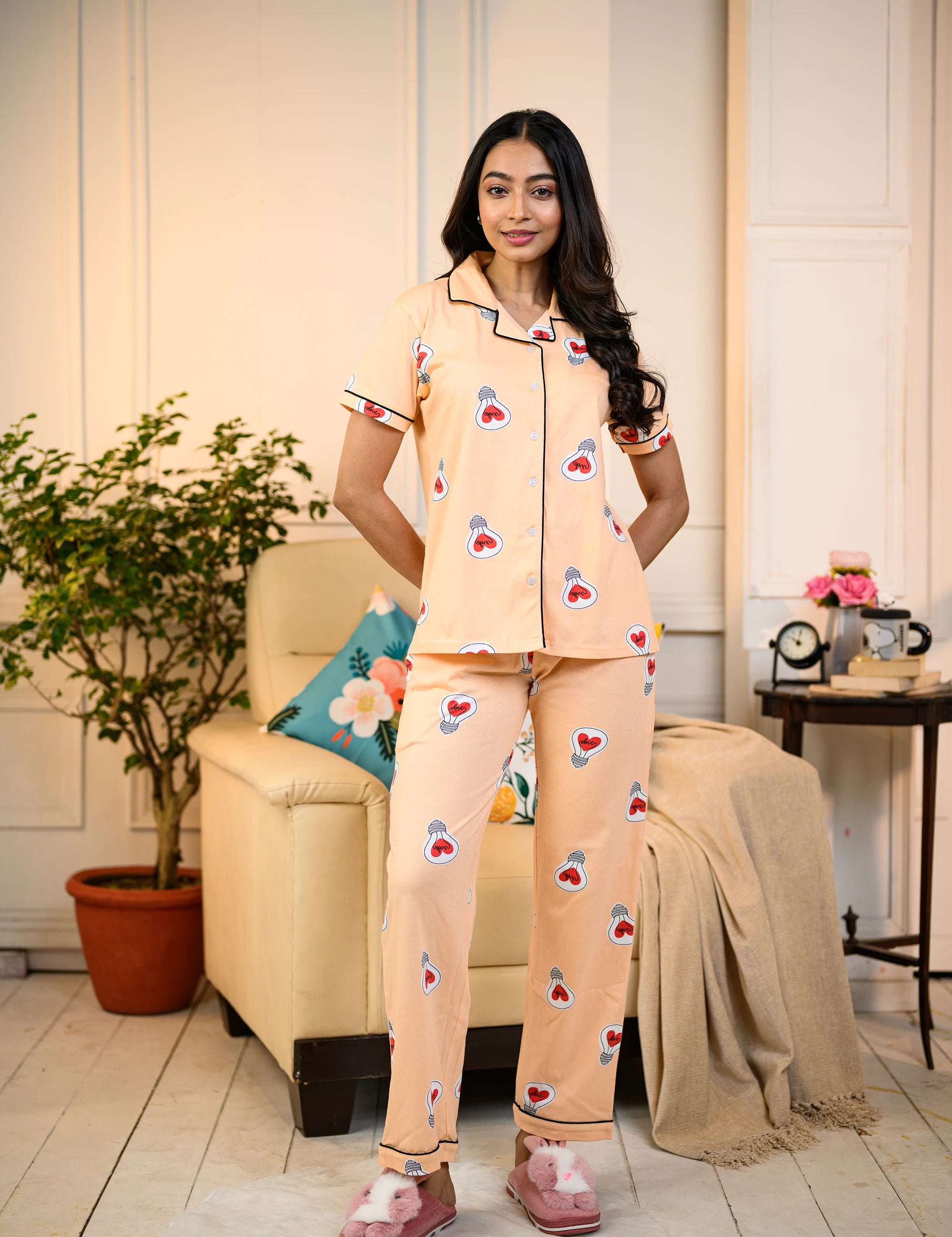 Woman standing in a peach Love Bulb Print Pyjama Set by NapStory, styled with playful bulb patterns, perfect for nightwear or lounging.