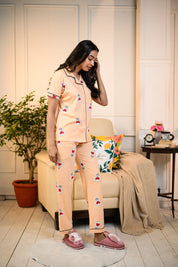 Side view of a lady wearing a peach Love Bulb Print Pyjama Set by NapStory, showcasing cute bulb designs in a cozy home setting.