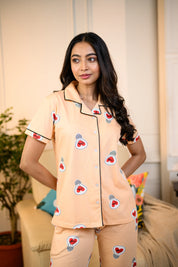 Woman wearing a peach Love Bulb Print Pyjama Set by NapStory, featuring cute bulb designs, styled for nightwear or loungewear.