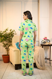 Back view of a woman wearing a green Sea Shell Print Pyjama Set by NapStory, showcasing colorful shell patterns and a relaxed fit.