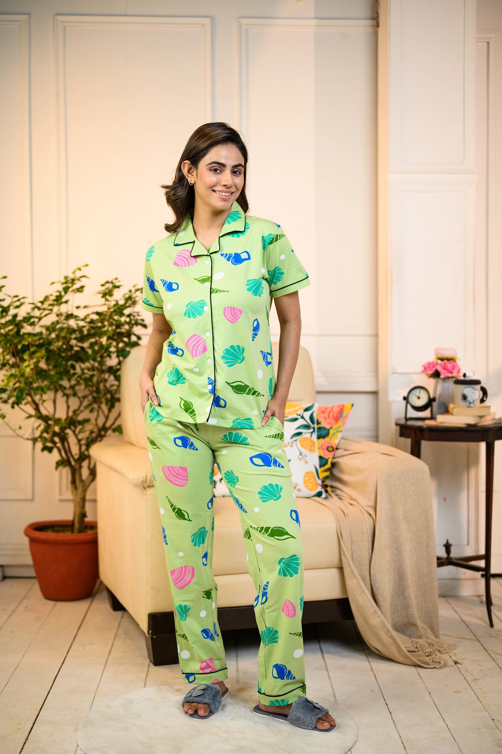 A young woman wearing a green Sea Shell Print Pyjama Set by NapStory, showcasing vibrant shell patterns, perfect for nightwear or loungewear.