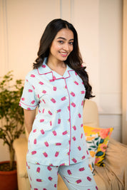 A woman smiles happily while wearing the Popsicle Print Pyjama Set by NapStory, radiating comfort and style.