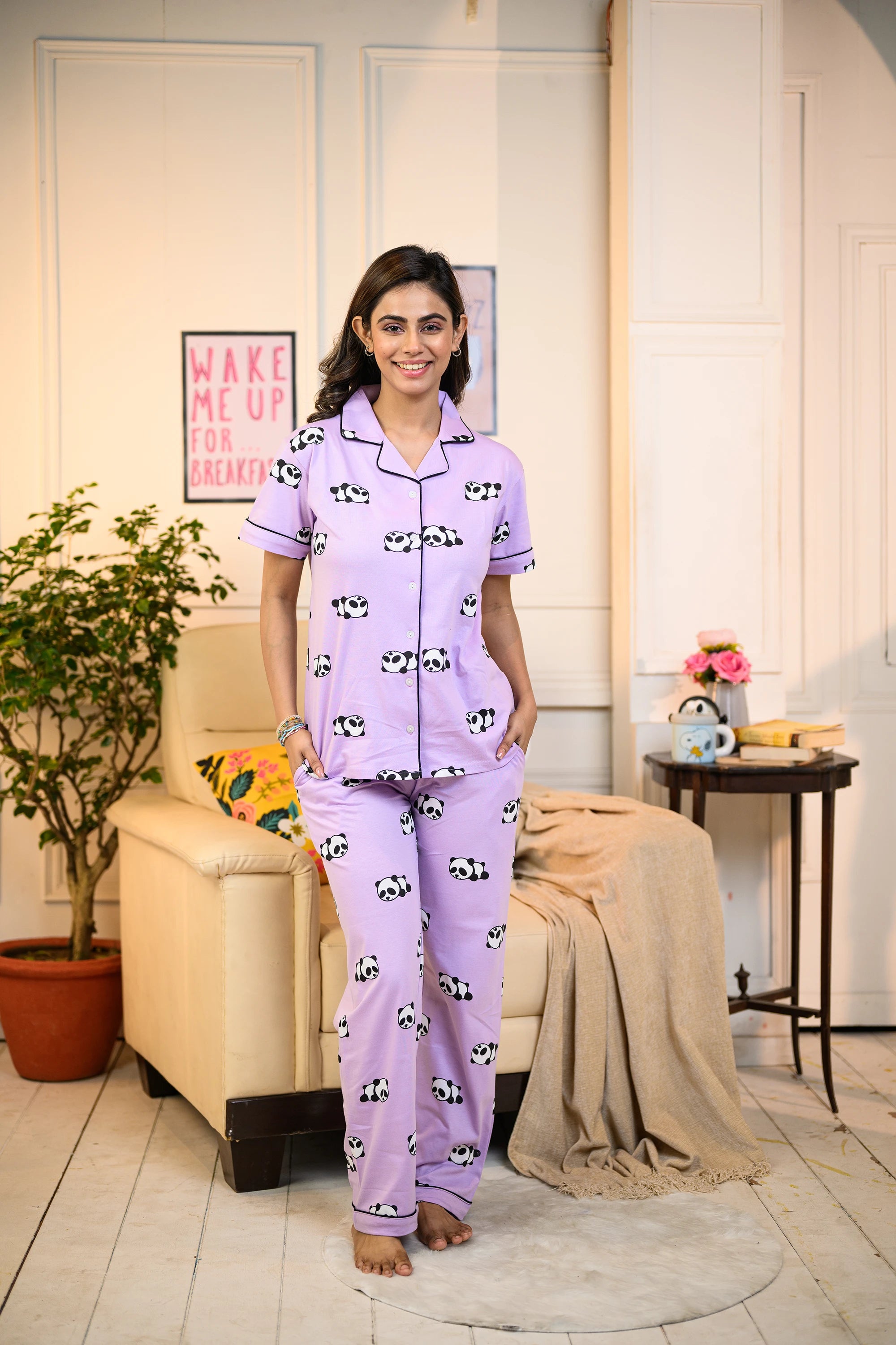 A woman standing confidently in a purple panda print pyjama set, with hands in pockets.