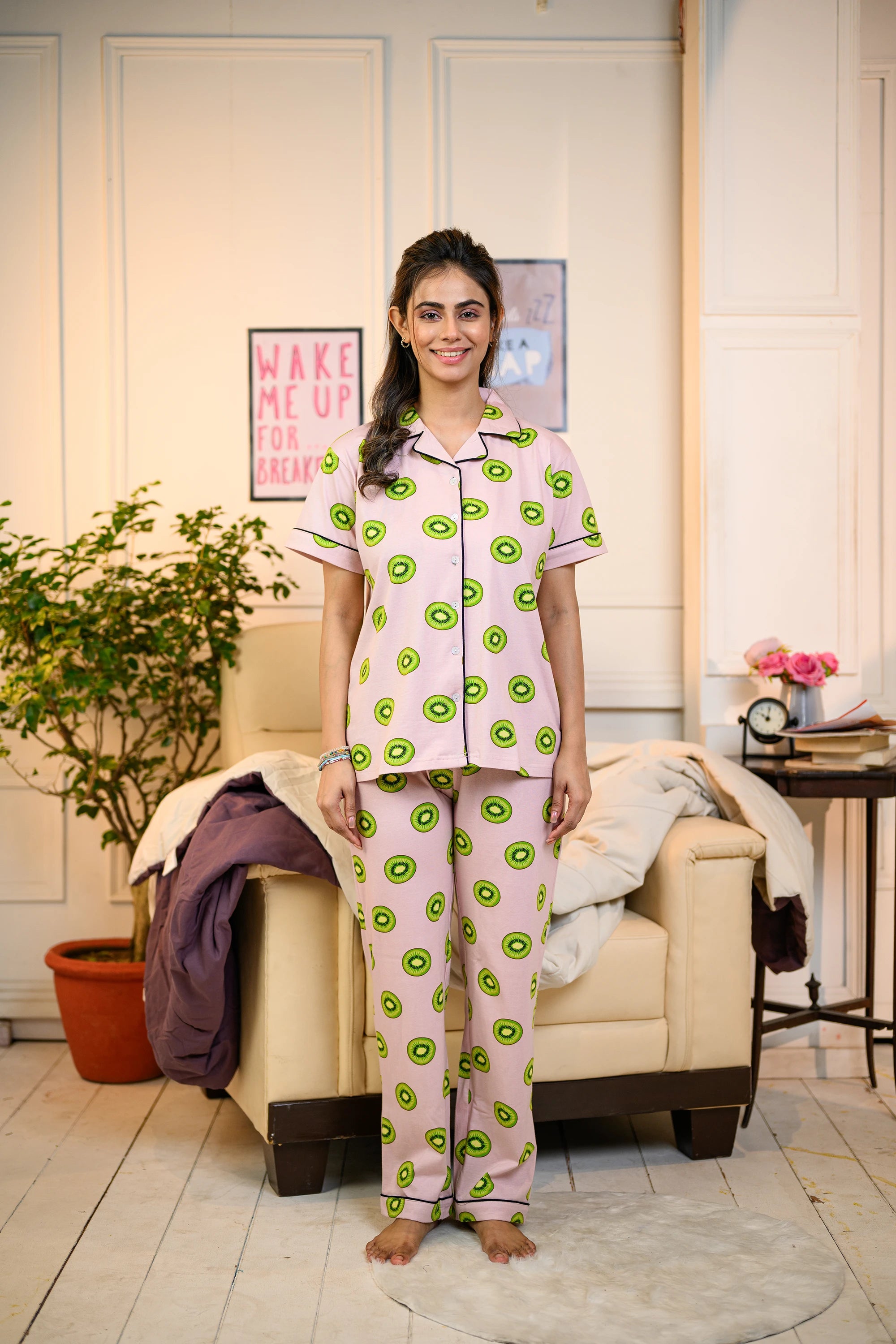 Full view of a woman in a relaxed pink Kiwi Print Pyjama Set by NapStory, showcasing vibrant kiwi patterns.