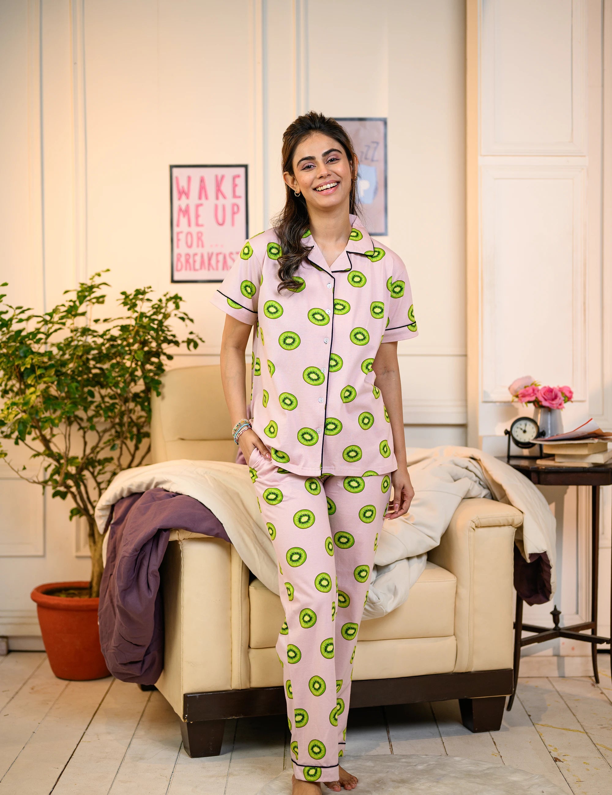 Kiwi Print Pyjama Set in pink by NapStory, worn by a woman in a cozy room, highlighting its refreshing and fun design.