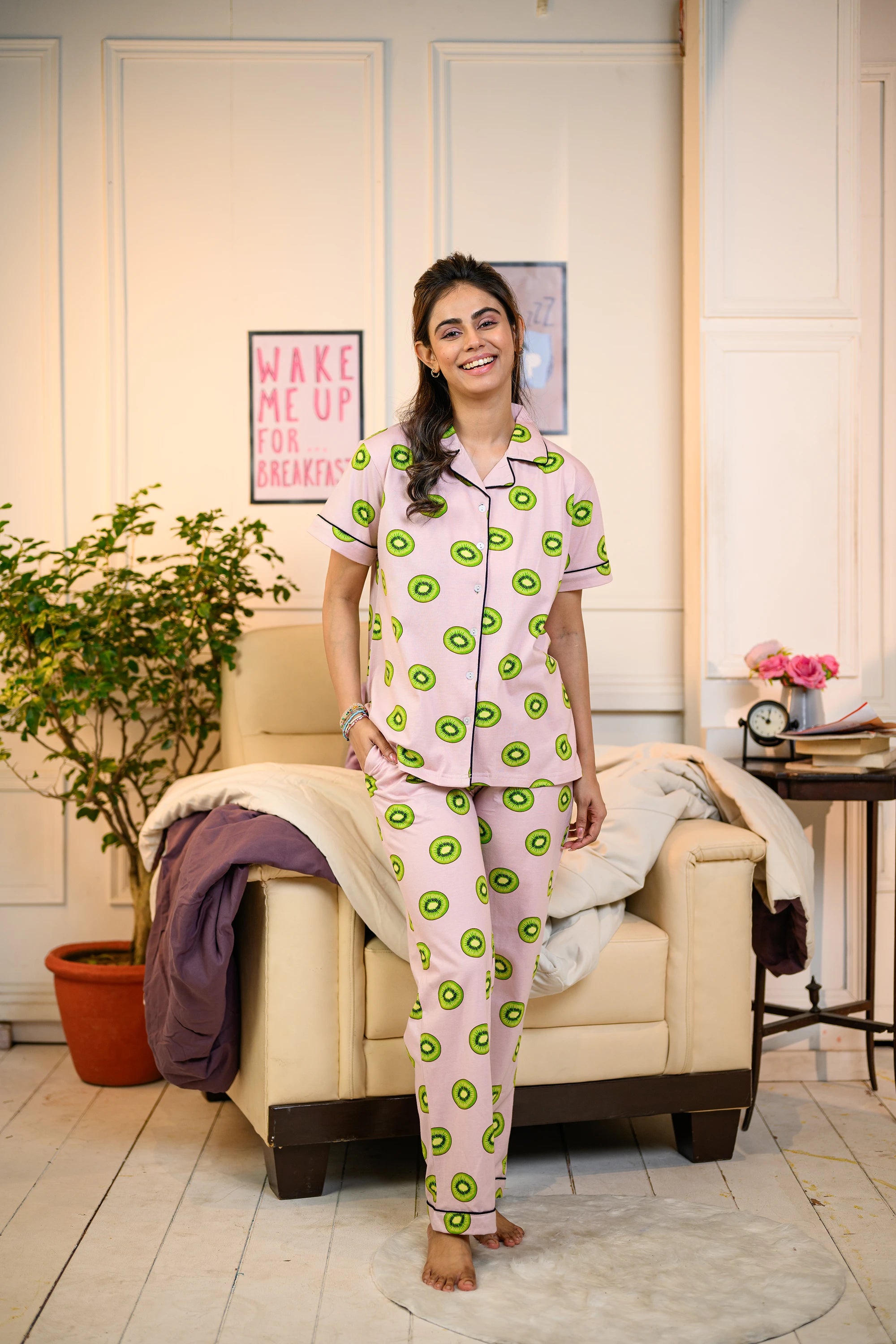 Kiwi Print Pyjama Set in pink by NapStory, worn by a woman in a cozy room, highlighting its refreshing and fun design.