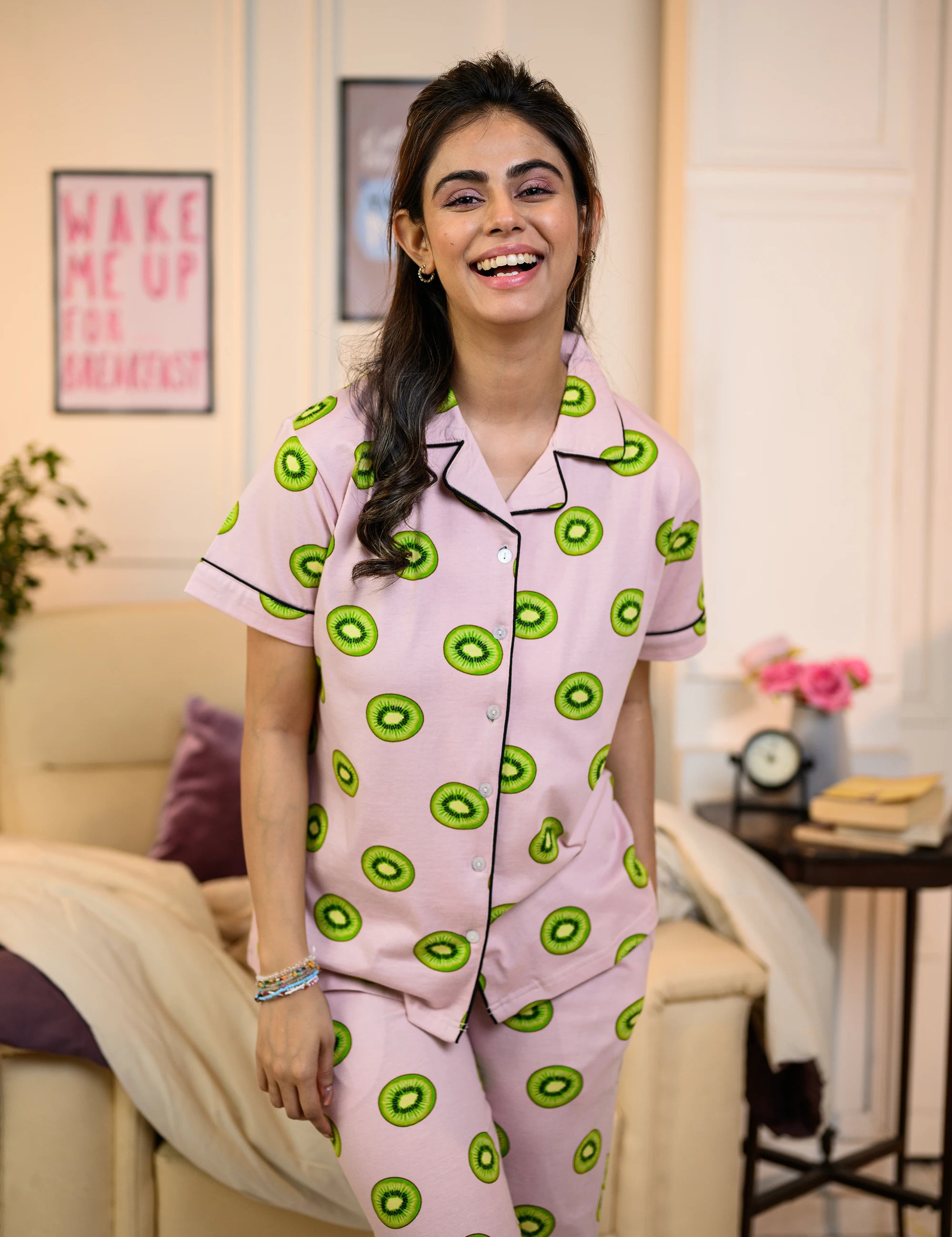 Woman wearing a pink Kiwi Print Pyjama Set by NapStory, featuring vibrant green kiwi patterns, styled for cozy nightwear.