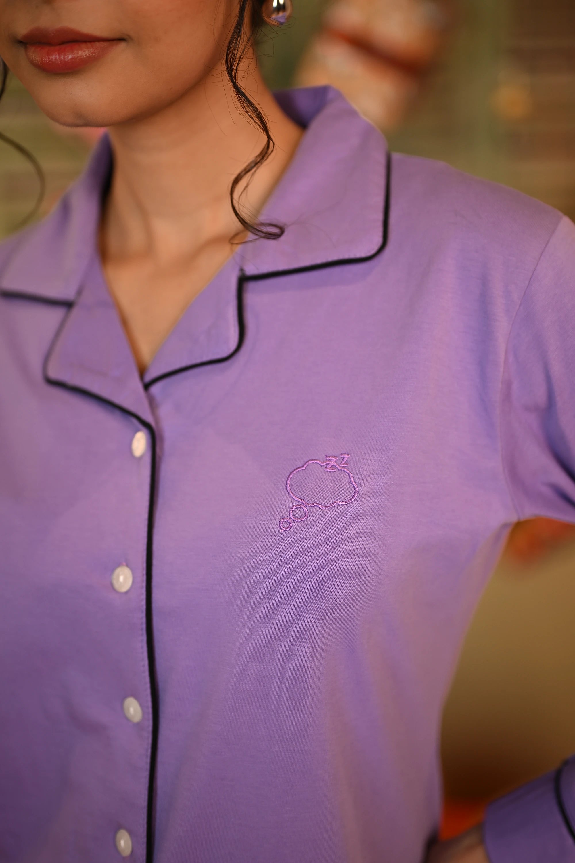 Close-up of a woman in a lavender full sleeve nightsuit set, showcasing the embroidered cloud design on her top.