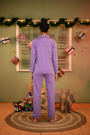 A woman in a lavender full sleeve nightsuit set, facing away from the camera with a calm and confident posture.