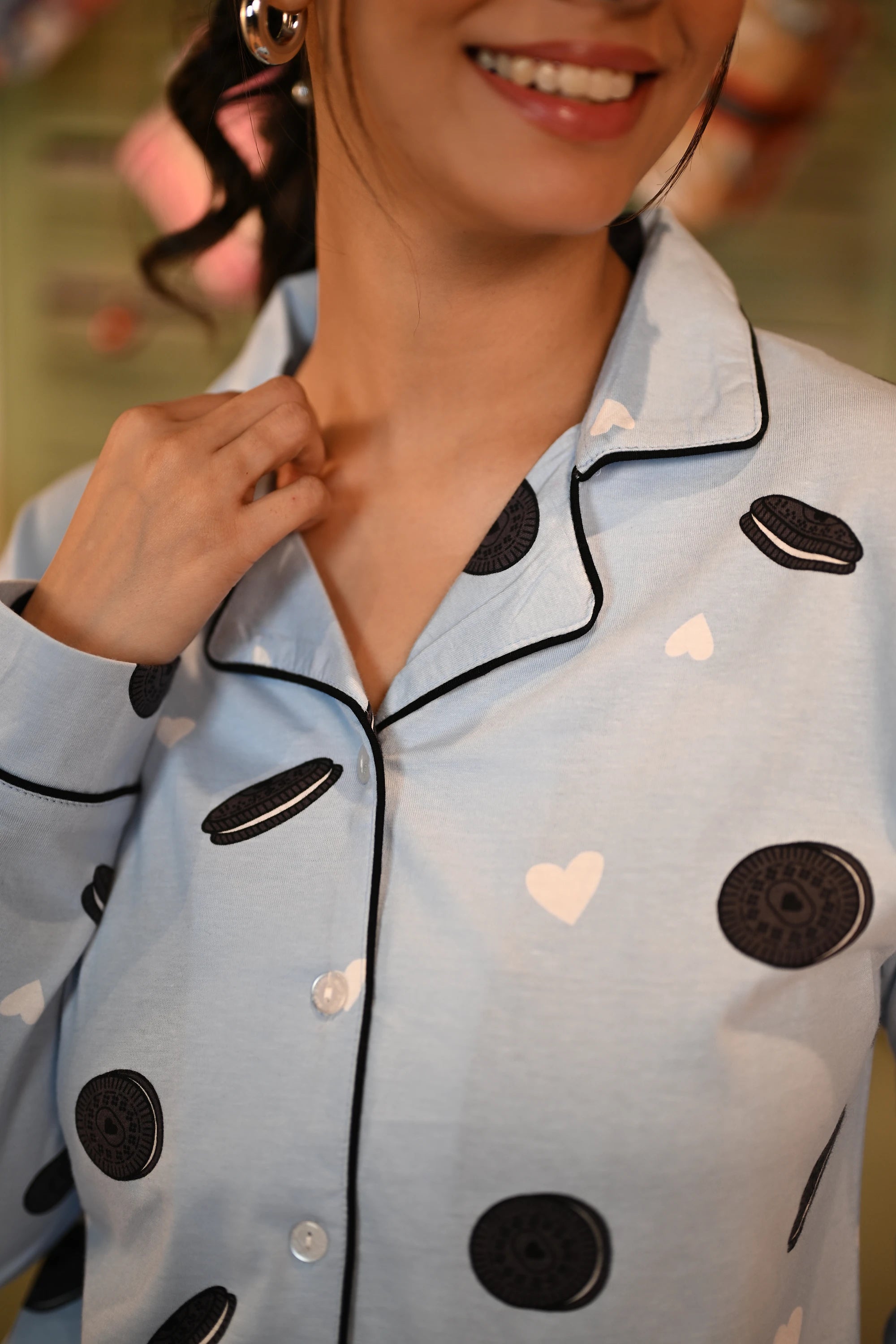 Close-up shot of a woman smiling and adjusting the collar of her Oreo print full-sleeve pyjama set.