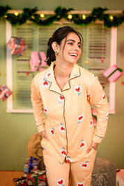 A close-up of a woman wearing a yellow full-sleeved pyjama set with a love bulb print, slightly leaning forward and smiling.