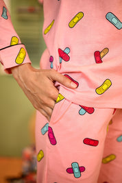 Close-up of the pyjama set fabric, showcasing the vibrant bandage print and the relaxed fit of the outfit, with one hand in the pocket for added style.