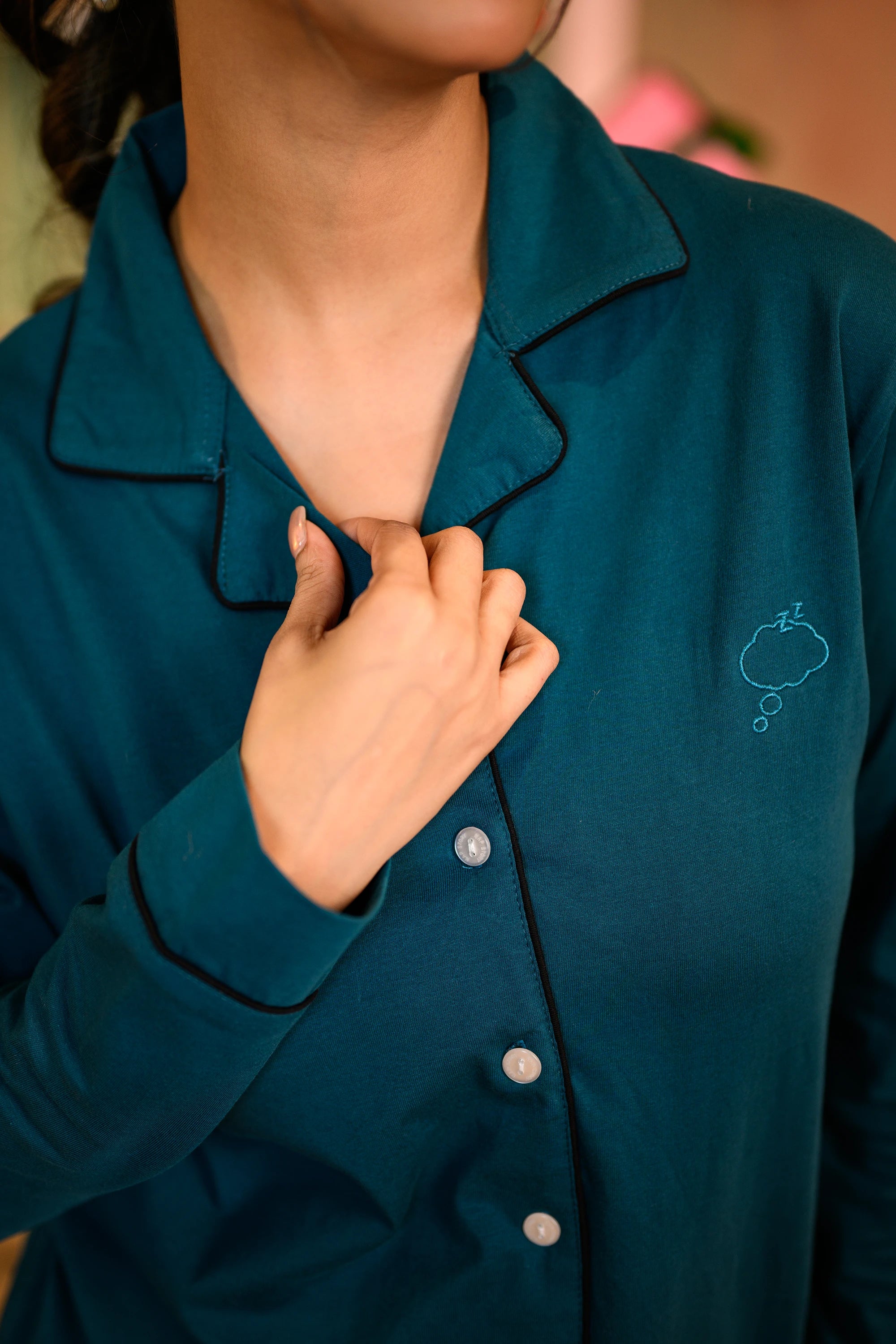 A close-up of a woman in a Teal Blue Full Sleeve Nightsuit Set, showcasing the button-up shirt with a playful sleeping cloud print. The soft fabric and delicate details make this nightwear a cozy and stylish choice for restful nights. 