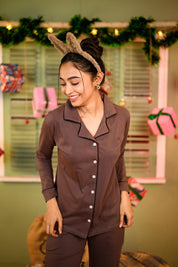 A woman smiling while wearing a Taupe Brown Full Sleeve Nightsuit Set, featuring a button-up top and matching pyjama pants, paired with a cute bunny ear headband. Cozy and stylish nightwear for women by NapStory.