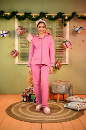 A woman smiling and standing in a pink full-sleeve pyjama set with a pocket. Cozy and stylish nightwear for women by NapStory.