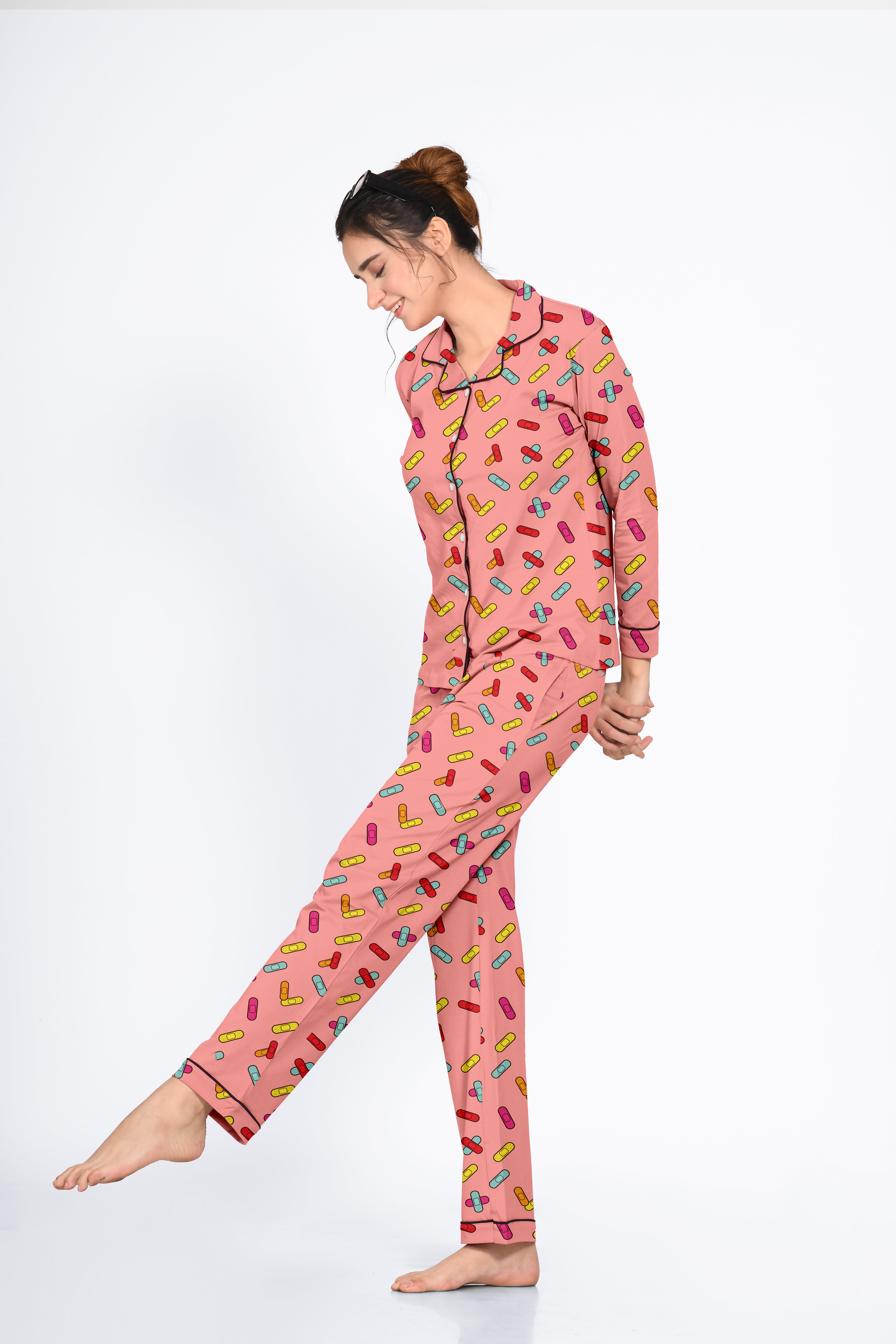 Woman in a pink Bandages Print Full Sleeves Pyjama Set by NapStory, striking a playful pose with a joyful smile.