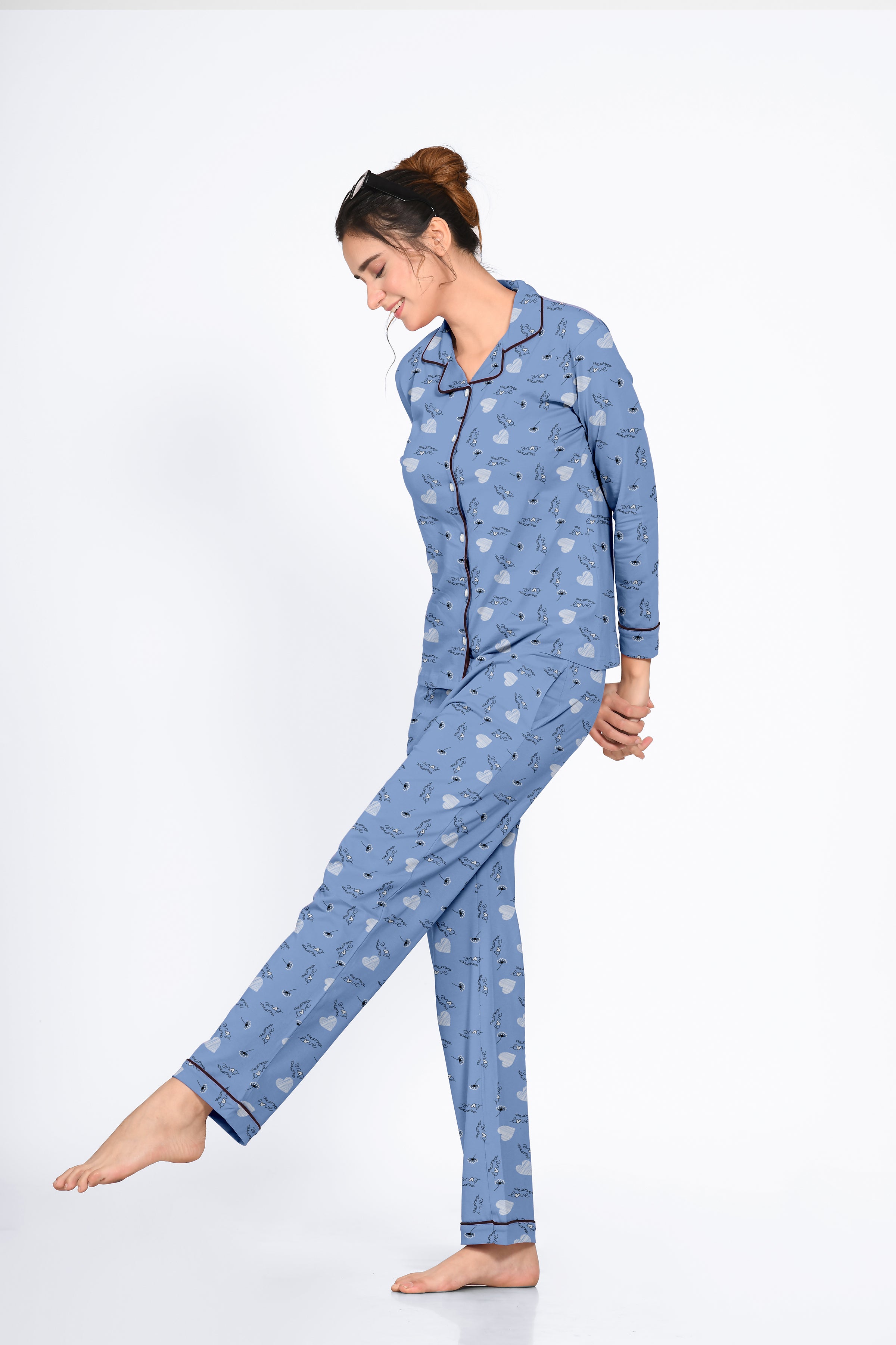 Woman wearing a blue Dandelion Print Full Sleeves Pyjama Set by NapStory, striking a playful and relaxed pose with a gentle smile.