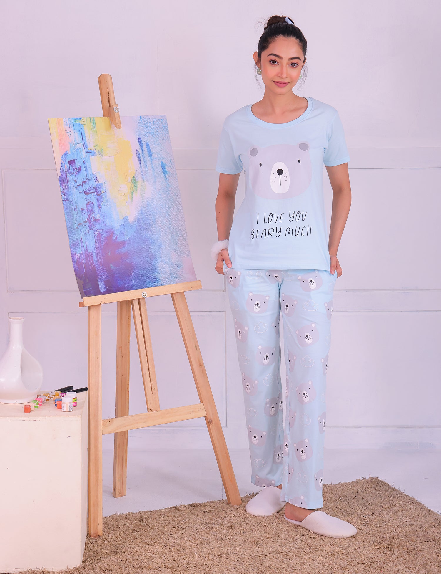 A girl standing next to a painting, wearing a Teddy Print T-shirt Pyjama Set by NapStory.