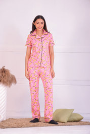 Image of a lady standing in Pink colour banana print night suit/ pyjama set