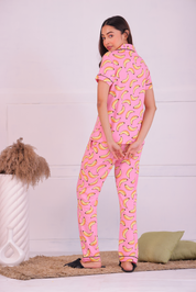 A young woman showing back view of her pink colour banana print nightwear pyjama set by Napstory