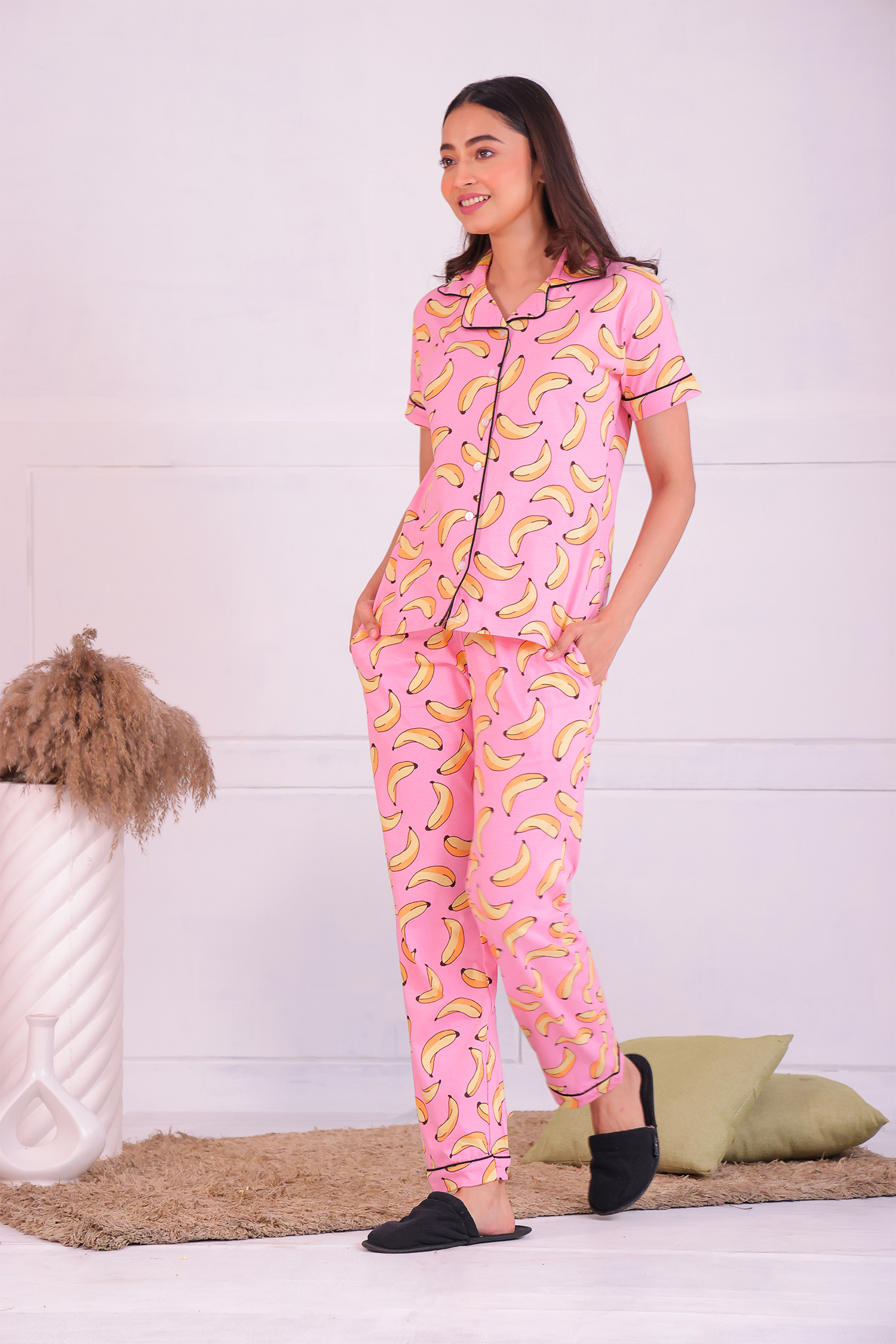 Image of a young woman walking in pink colour banana fruit print nightwear pyjama set by Napstory