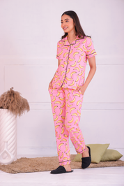 Image of a young woman walking in pink colour banana fruit print nightwear pyjama set by Napstory