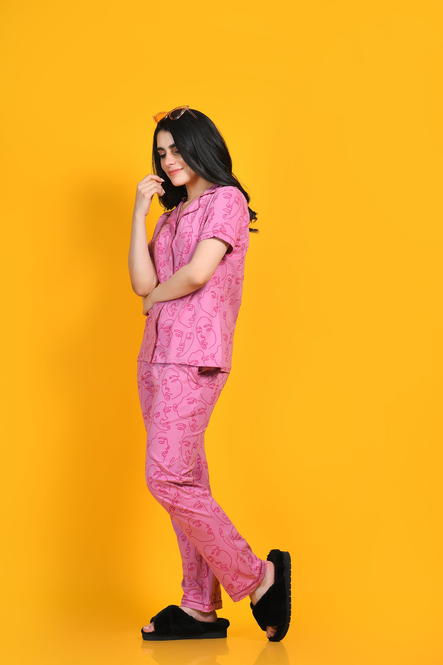 A young woman in nightwear pyjama set standing against a yellow background