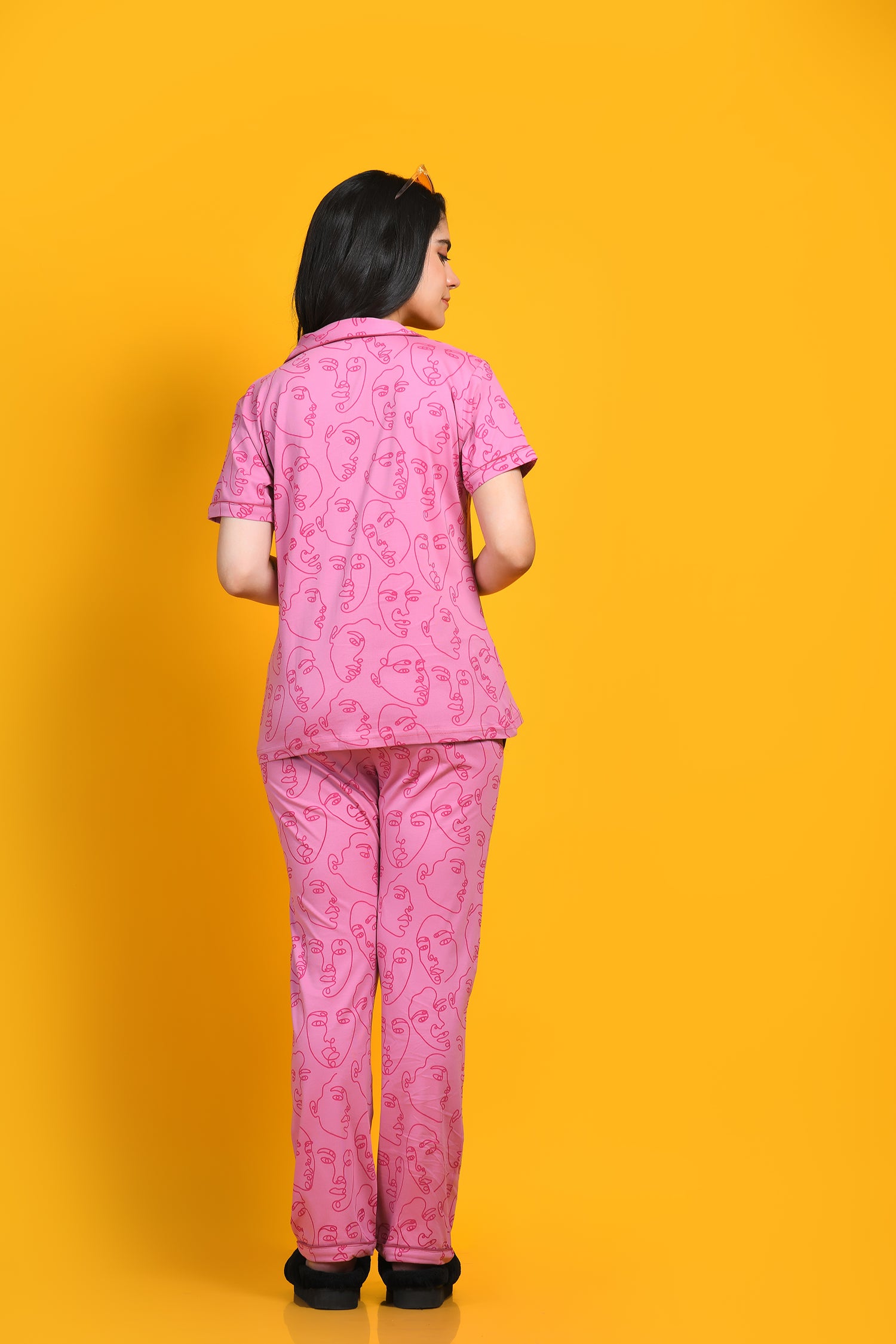 A young woman in nightwear pyjama set standing opposite a yellow background