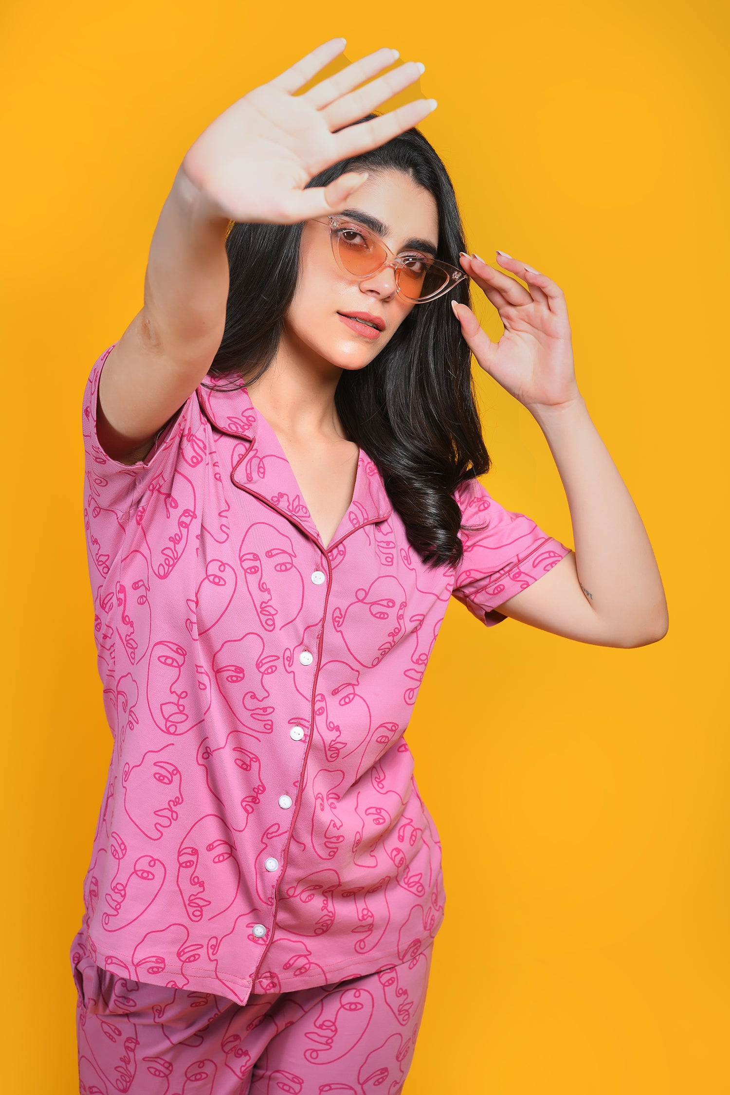 A young woman in human face print pink colour nightwear pyjama set showing right hand