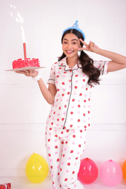 A girl wearing a Lovebug print nightwear pyjama set by NapStory and holding a cake.